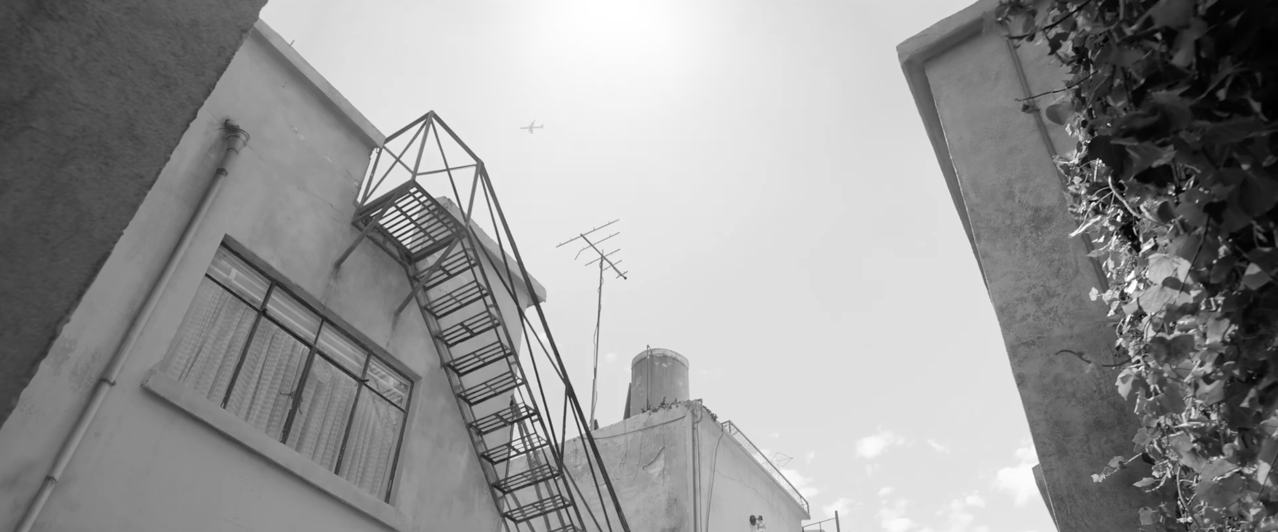 Exterior of the family home with rooftop stairs and an airplane overhead