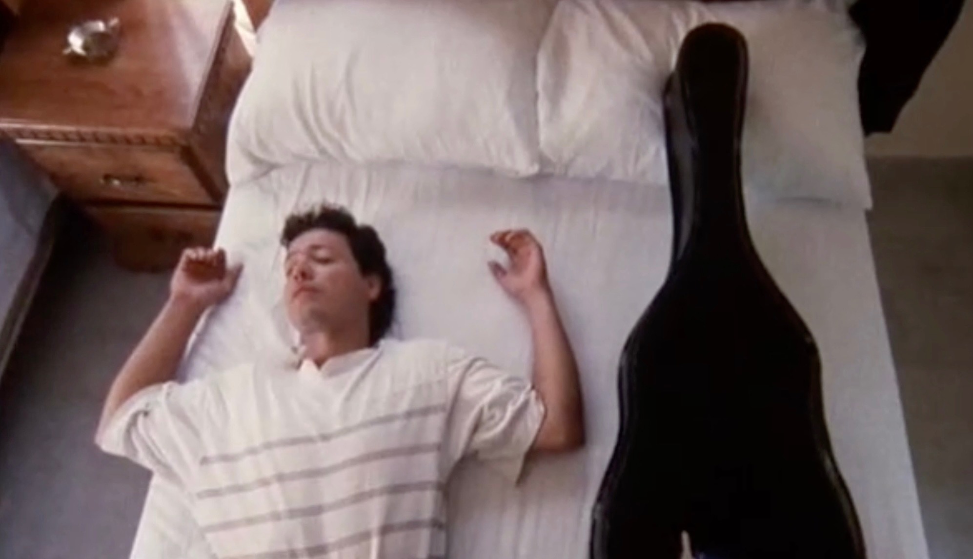 mariachi laying on bed with guitar