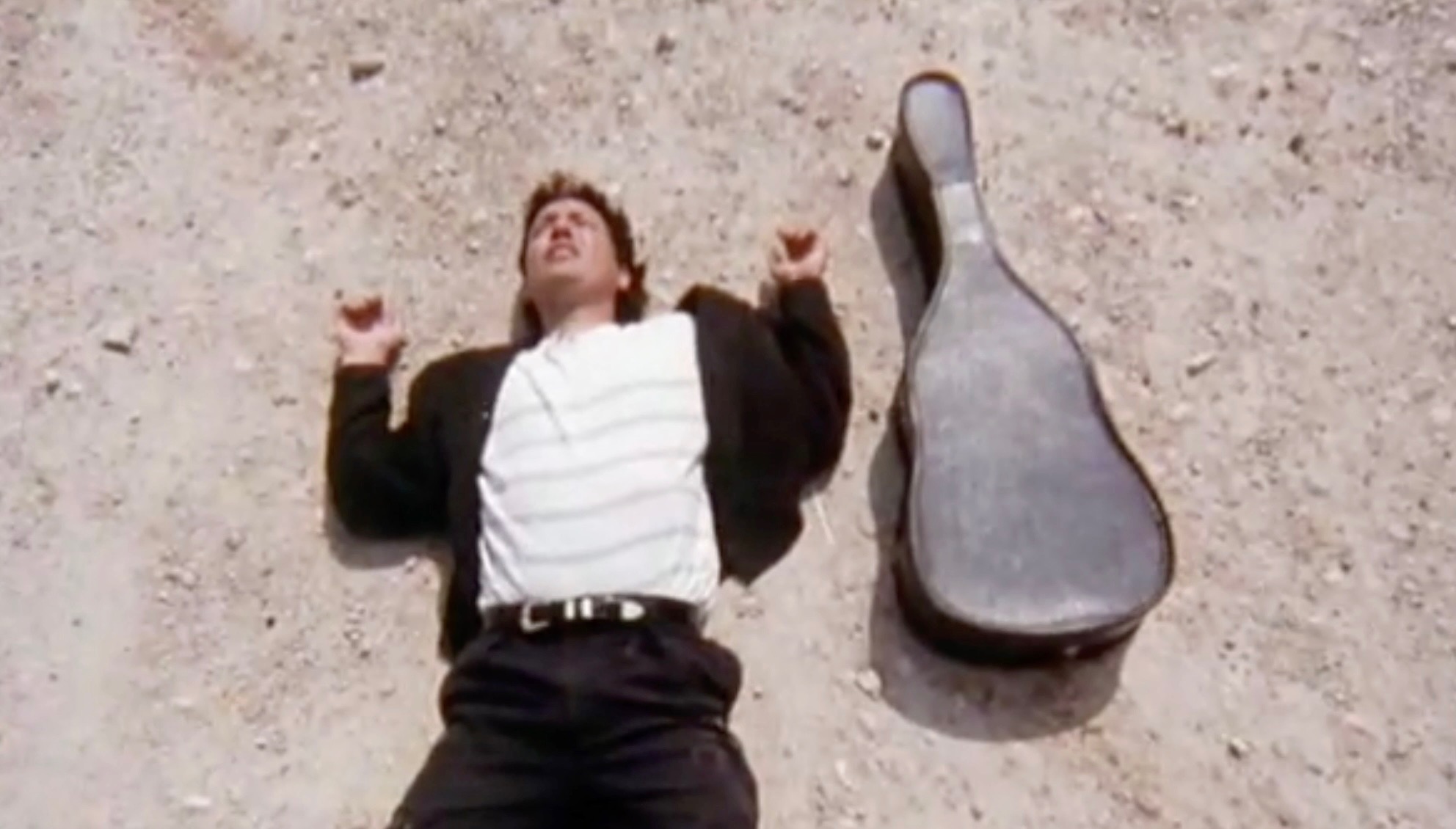 mariachi laying in desert with guitar