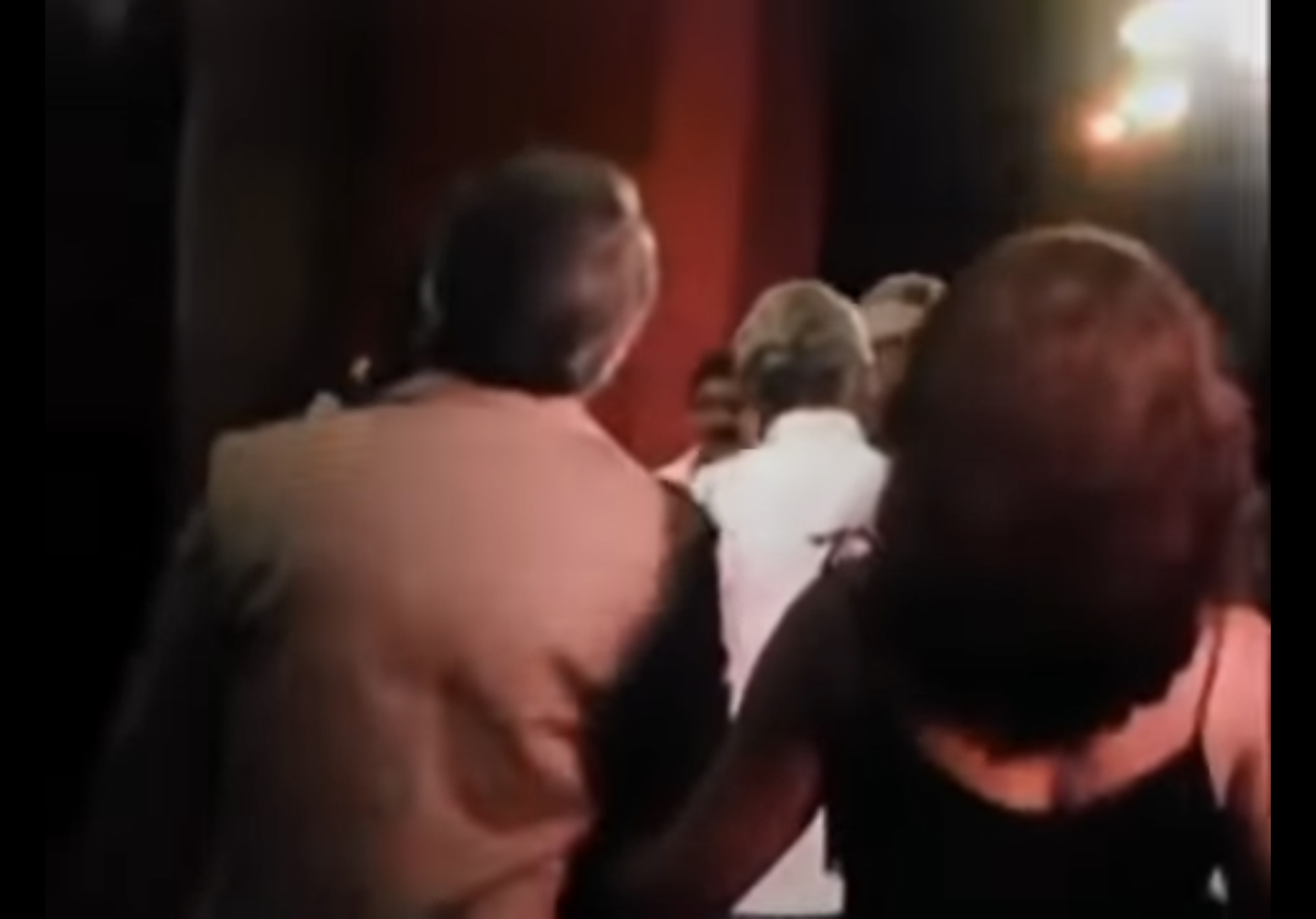 Camera views the back of people's head as they head out to congratulate Oscar on his play. 