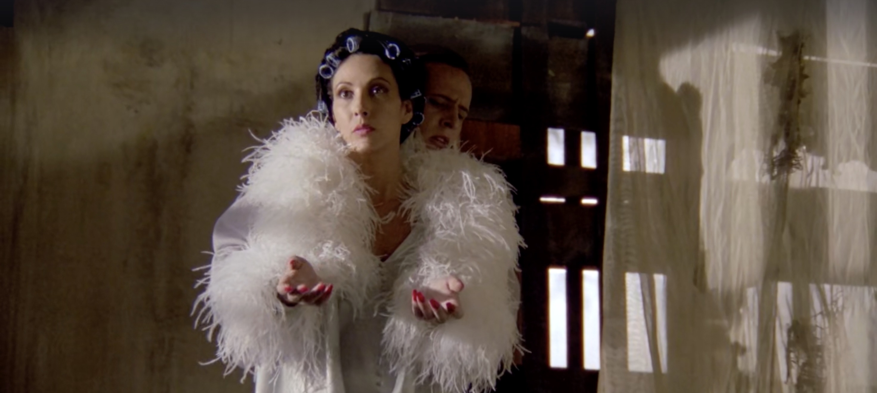 Fénix’s own dress is symbolically of use, too: in youth, circus outfits imposes innocence within spectacle, and in adult life, his pallid skin and tortured appearance mark trauma. When he moves, thus acting as his mother’s “arms,” the two figures become merged into a unitary grotesque form, visually embodying themes of control, dependence, and divided self.