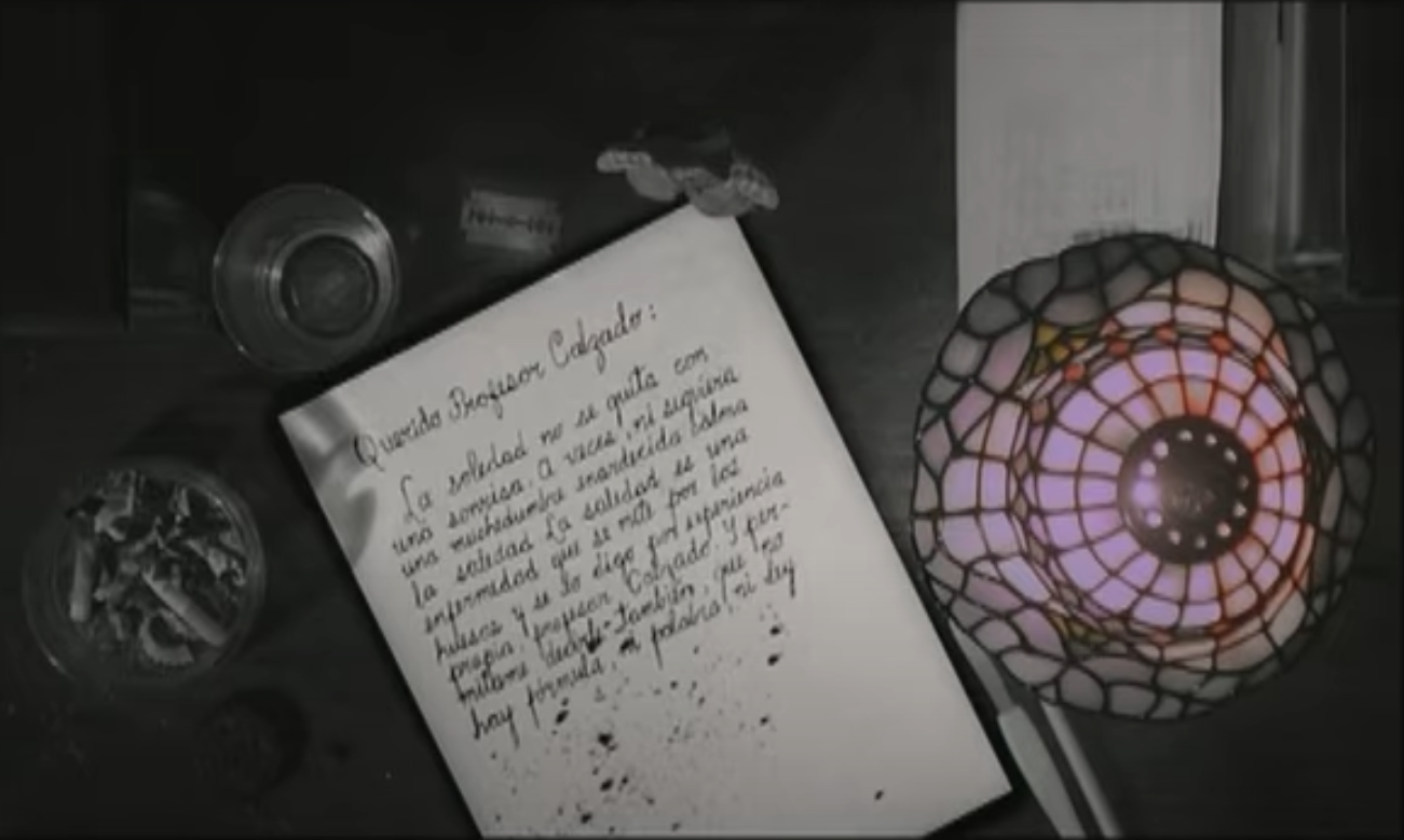 Desk with Carla's letter, cigarettes, alcohol, chocolate, and a lamp
