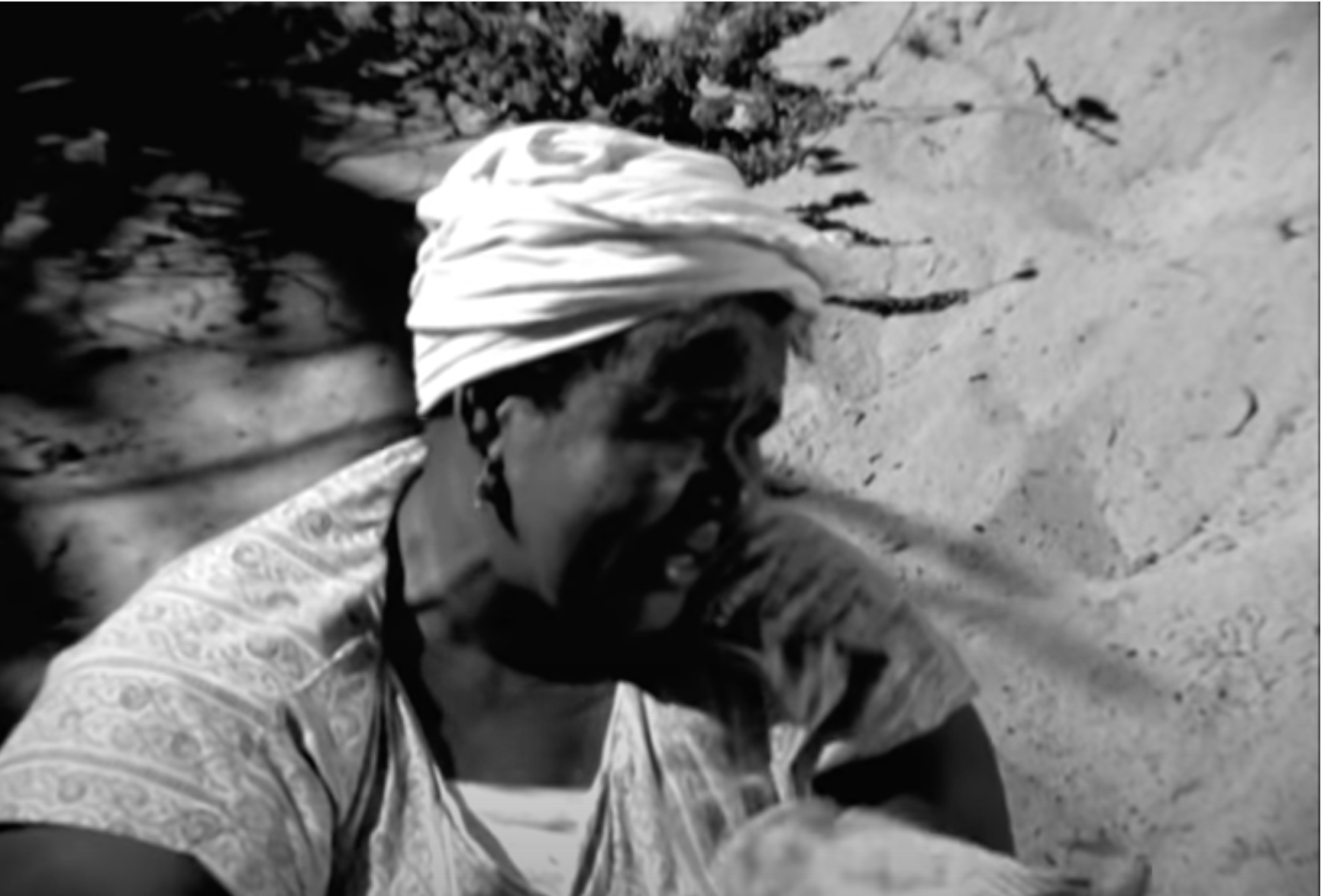 A woman sitting against the sand.