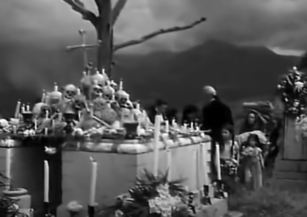 Macario and his family approach a grave decorated for Día De Los Muertos