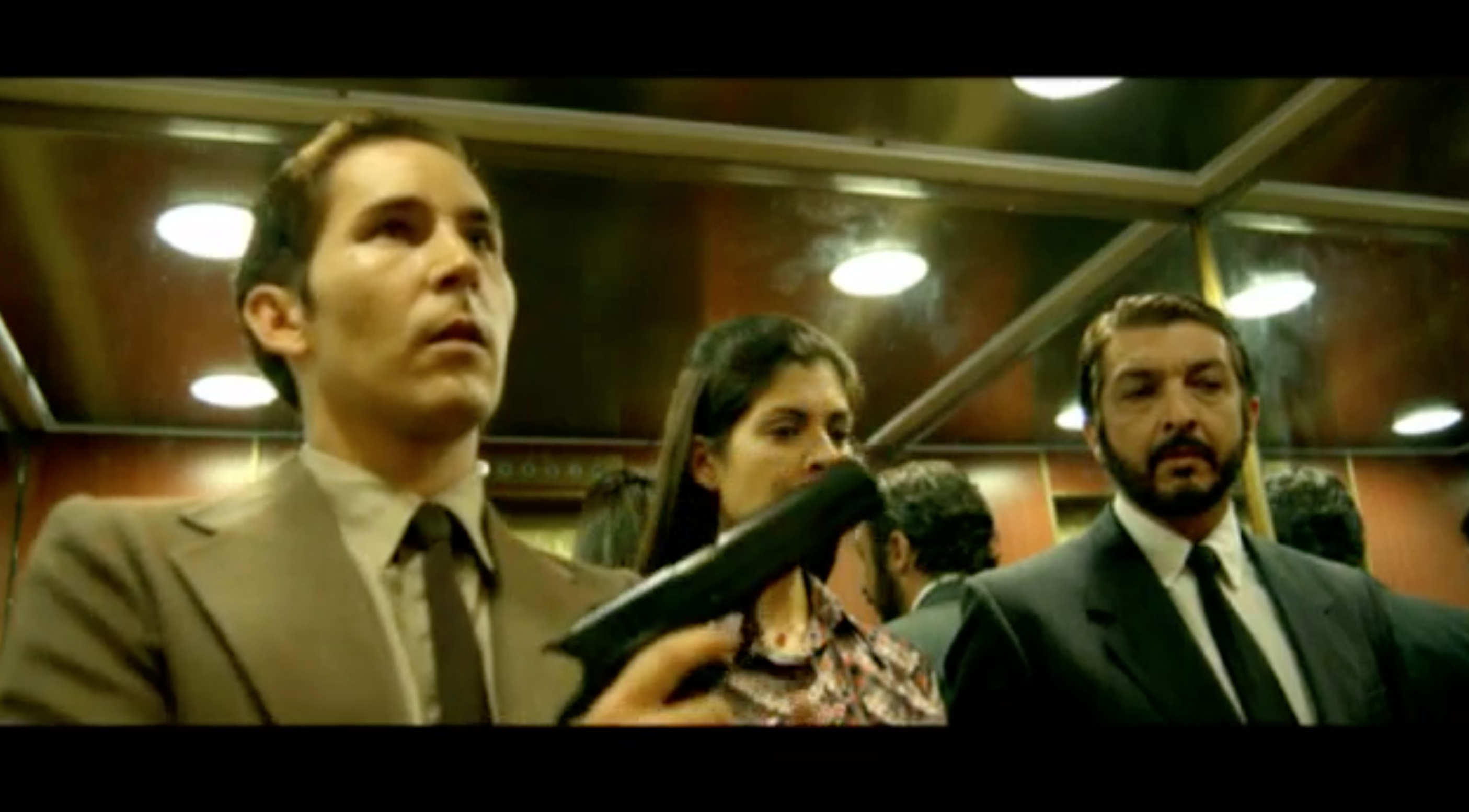 We see Isidoro Goméz showcase his gun in front of the agents while all together in an elevator. There is surprise and uneasiness in Irene's eyes.