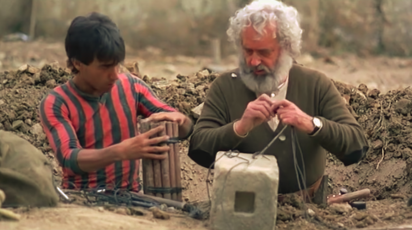 Jacinto helps prepare charges of dynamite with visible holes in his clothing. 