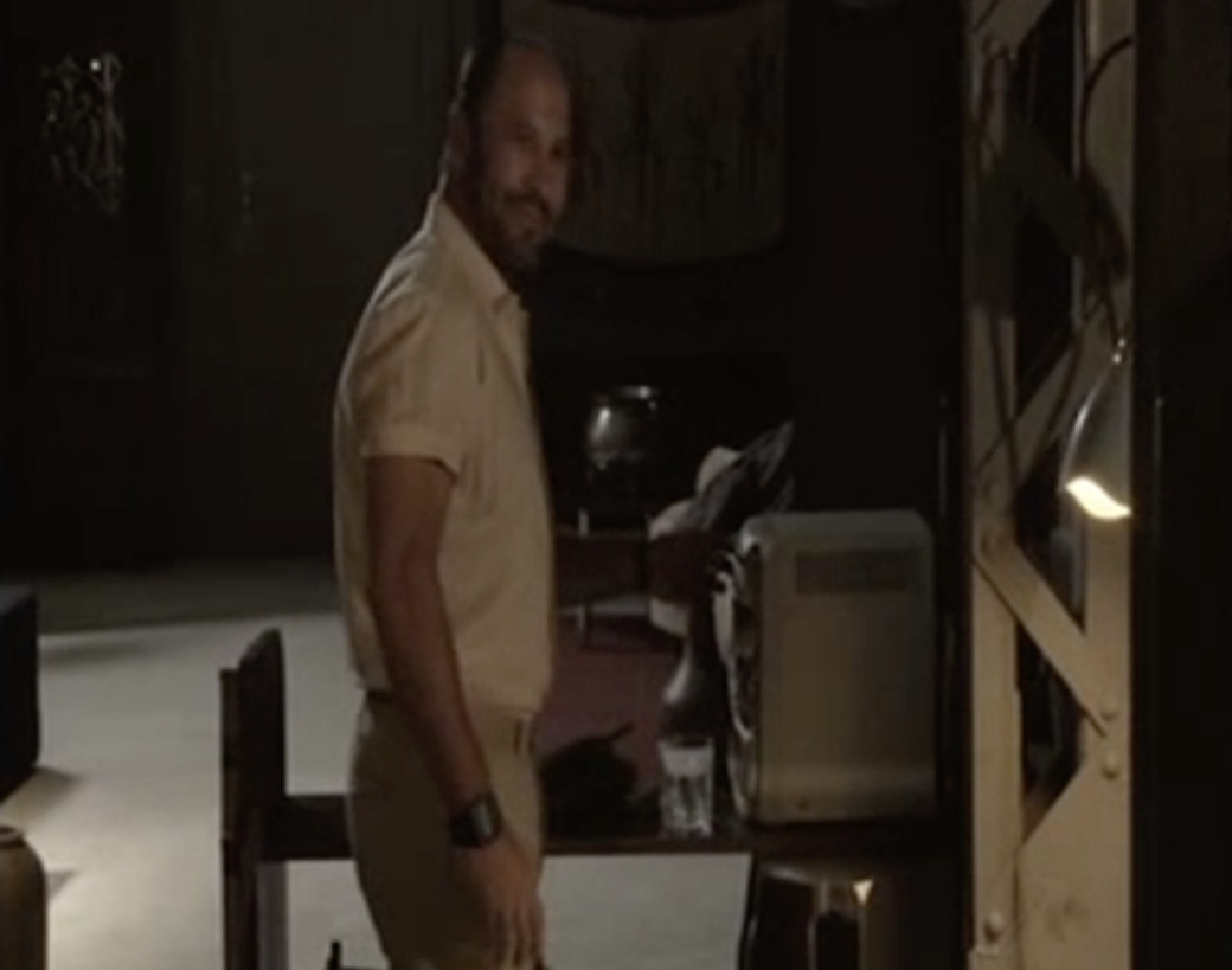 Alfredo en su apartamento. El fondo es muy oscuro y vacío.