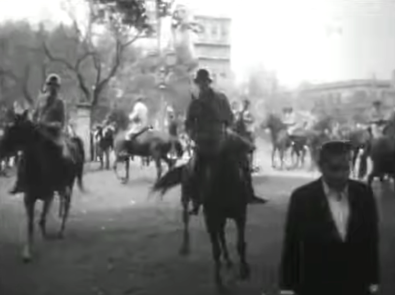 Mounted riot police on horseback command the middle ground in a scattered yet imposing patrol pattern, while a civilian in a suit walks through the foreground.