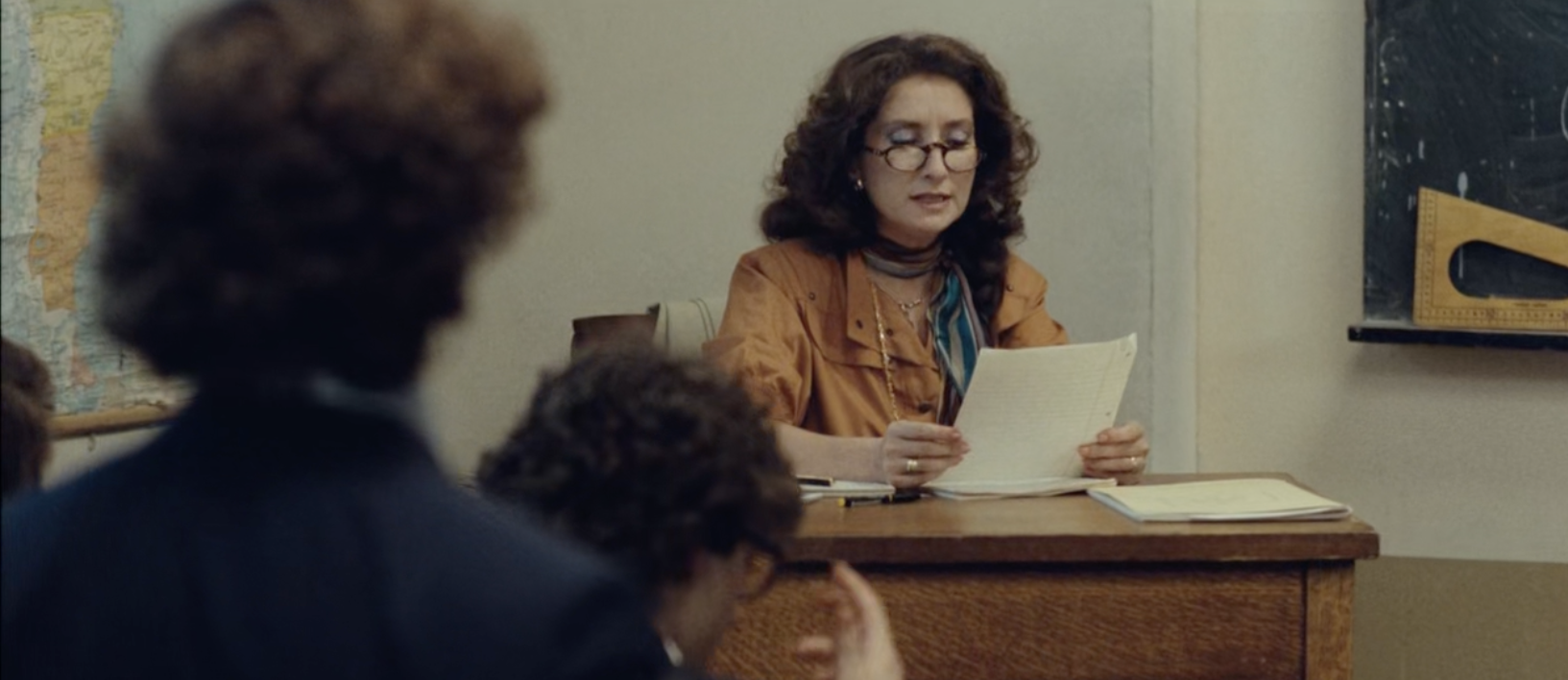Alicia can be seen wearing looser clothing as she reads one of her students essays regarding the realities of the regime