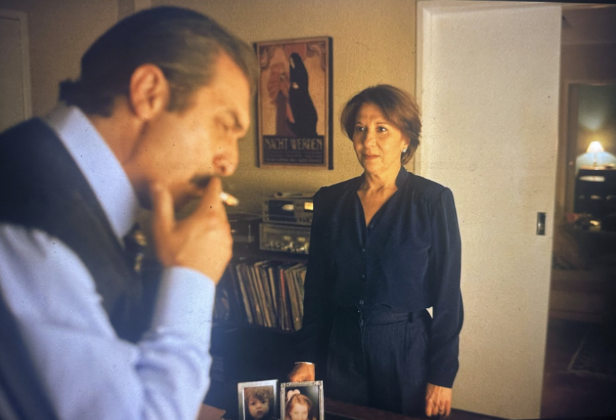 The Strasseras discuss the case with photos of their children at the base of the camera frame.