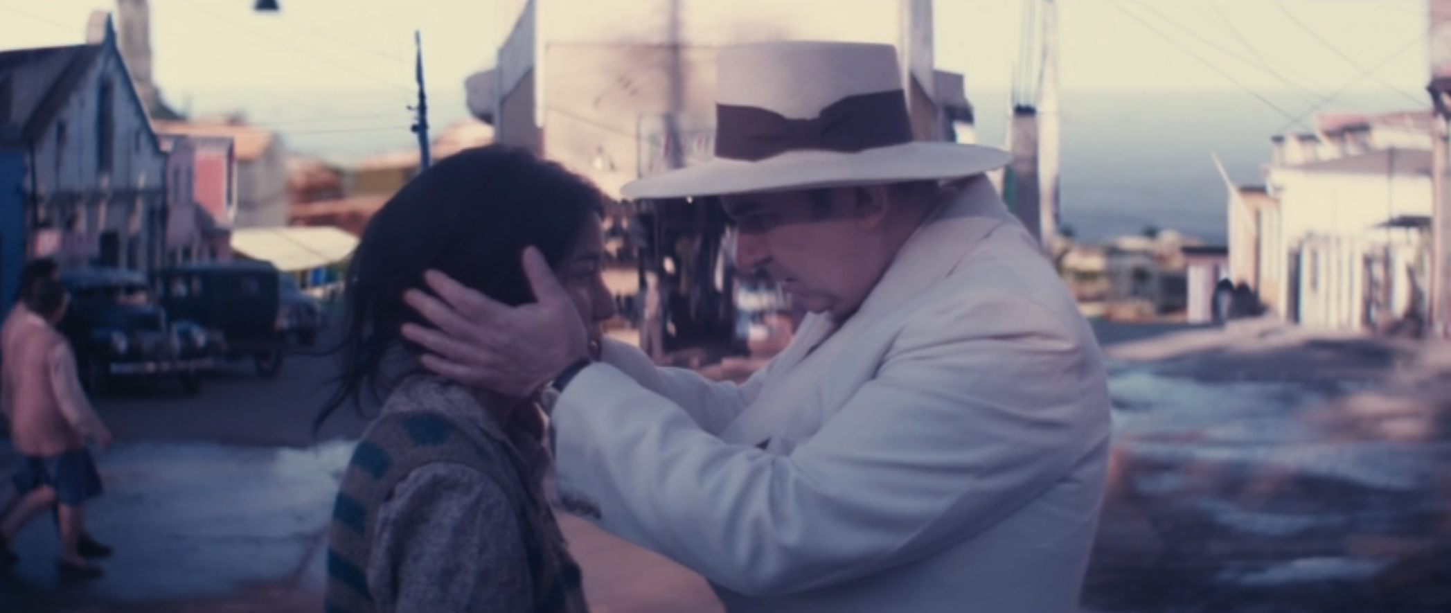 Neruda, dressed in all white, embraces a peasant girl.