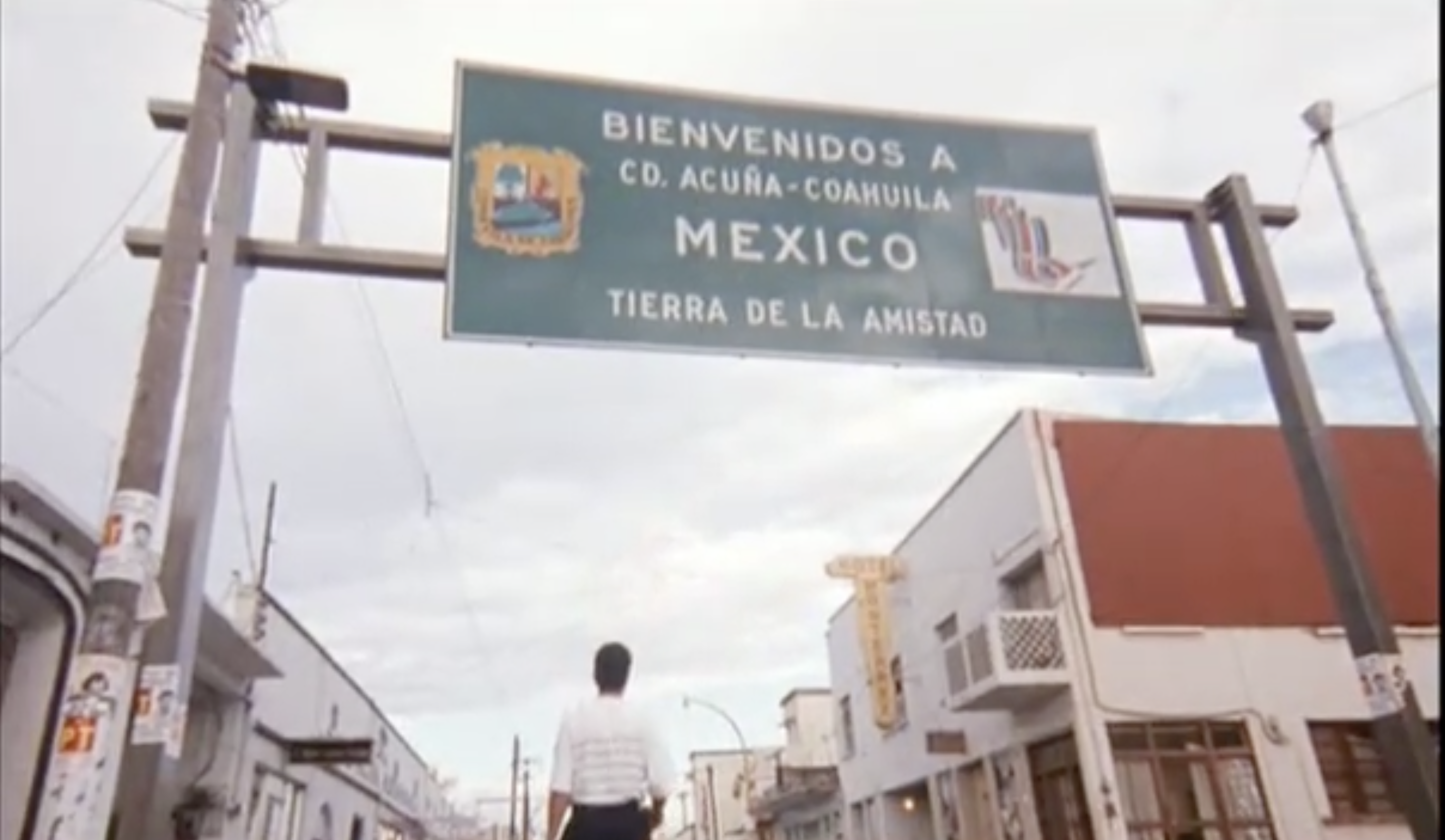 Mariachi walking beneath Coahuila sign