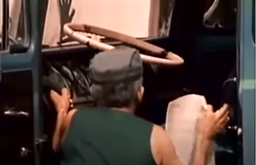 There is a truck driver getting into his truck.