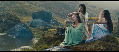 woman bathed by others on cliffs.