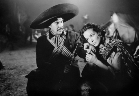 Black-and-white still from La Cucaracha (1959) showing Colonel Antonio Zeta and Cucaracha in a tense exchange at a nighttime military camp.